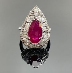 This pear-shaped ruby ring is perfect for special occasions, symbolizing love and grace, and is a stunning addition to your jewelry collection. With its classic and evocative design, it's sure to be cherished as a captivating and meaningful piece of jewelry. Details: 18K Gold - 7.85 Gms  Ruby - 5.00 Ctw Diamond Pear Shapes - 1.64 Ctw Diamond Rounds - 0.54 Ctw Diamond Ruby Ring With Prong Setting In Pear Shape, Formal Teardrop Ruby Ring In Fine Jewelry Style, Classic Teardrop Ruby Ring For Formal Occasions, Teardrop Ruby Ring For Formal Occasions, Teardrop Ruby Ring With Diamond In Fine Jewelry Style, Formal Teardrop Ruby Ring Fine Jewelry, Fine Jewelry Ruby Ring With Marquise Halo, Fine Jewelry Marquise Ruby Ring With Halo Setting, Teardrop Ruby Ring In Fine Jewelry Style