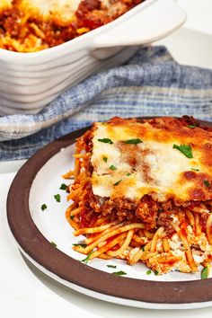 a white plate topped with lasagna next to a casserole dish