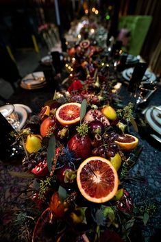 a long table is set with fruit and silverware for an elegant dinner party setting