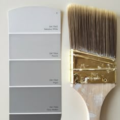 a paintbrush with some different shades of gray on it next to a white wall