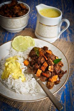 a plate with rice, meat and sauce on it next to two bowls of soup