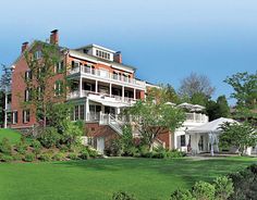 a large red brick building sitting on top of a lush green field next to trees