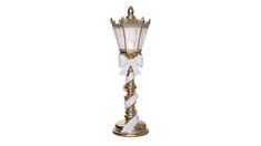 a white and gold lamp with a bow on it's side, against a white background