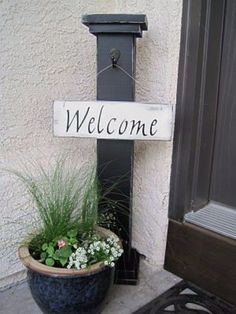 a welcome sign is attached to the side of a building with potted plants in it