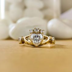 a gold ring with a heart shaped diamond in the center and two smaller diamonds on each side