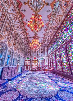 an ornate room with chandeliers and stained glass windows in the ceiling is lit by colorful lights