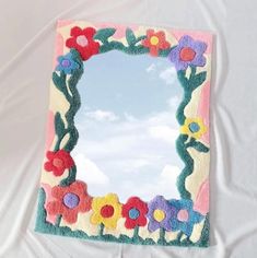 a mirror that is on top of a white sheet and has flowers painted on it