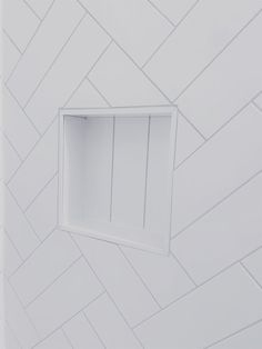 a white bathroom with a square window in the wall and herringbone pattern on the walls