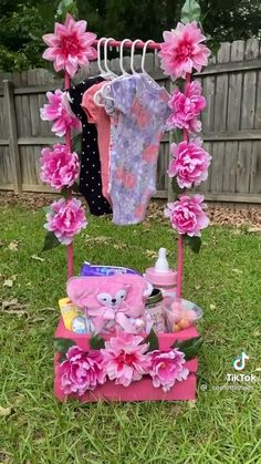 a baby's clothes rack with pink flowers and teddy bears on it in the grass