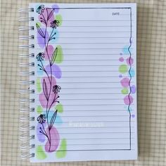 a notepad with flowers on it next to a pen