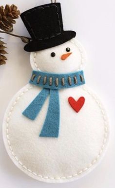 a felt snowman ornament with a black hat and blue scarf on it