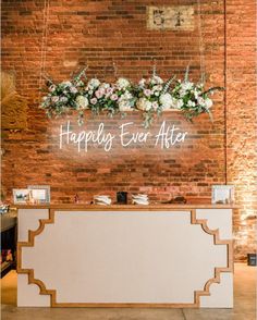 a sign that says happily ever after hanging from the side of a brick wall next to a reception table