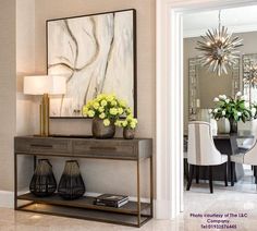 a dining room table with vases and flowers on it in front of a painting