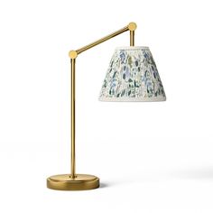 a lamp that is sitting on top of a white surface with a green and blue flowered shade