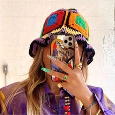 a woman is taking a selfie with her cell phone while wearing a colorful hat