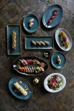 a table topped with plates and bowls filled with different types of sushi dishes on top of each other