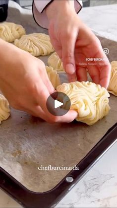 a person is making dumplings on a baking sheet with a video screen in front of them