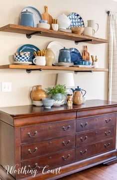 a wooden dresser topped with lots of dishes and cups on top of it's shelves