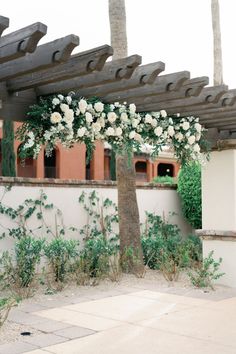 an outdoor wedding setup with white flowers and greenery on the side of a building