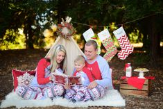 a man and woman sitting on the ground reading a book to a child in pajamas