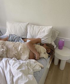 a woman laying in bed with two dogs on her back and one dog sleeping next to her