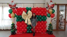 a woman standing in front of a giant balloon arch with santa clause decorations on it