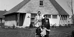 an old black and white photo of people standing in front of a house with two children