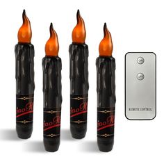 three black candles with orange flames next to a remote control