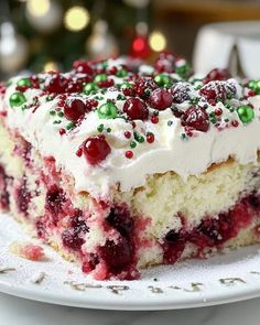 a white plate topped with a piece of cake covered in frosting and cranberries