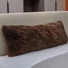 a brown pillow sitting on top of a white bed