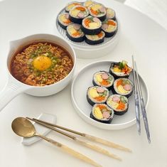 two plates with sushi and chopsticks next to a bowl of ramen