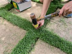 someone is using a hammer to cut grass in the shape of a letter t on the ground