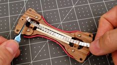 someone is working with a miniature instrument made out of wood and metal parts on a table