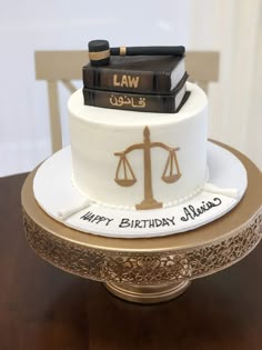 a law themed birthday cake with books and scales on the top, sitting on a table