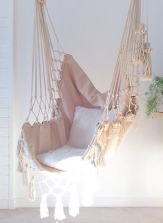 a hammock hanging from the ceiling in a room with white walls and wood flooring