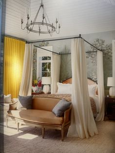 a canopy bed with curtains hanging from it's sides and a couch in the foreground