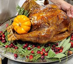 a roasted turkey on a platter with cranberries and greenery