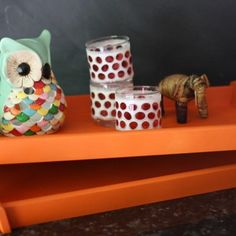 an orange tray with candles, owl figurines and other decorative items on it