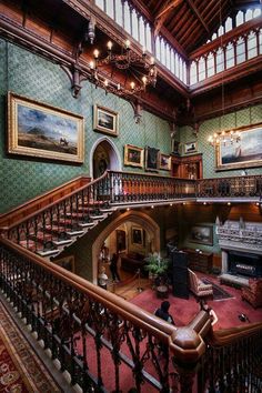 an ornate staircase in the middle of a room with paintings on the walls and wooden railings