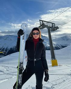 a woman standing in the snow with skis on her feet and holding onto a ski lift