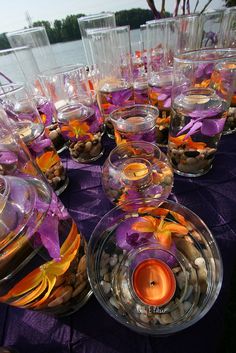 there are many glass bowls with orange and purple flowers in them on the table next to each other