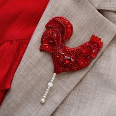 a red rooster brooch sitting on top of a suit