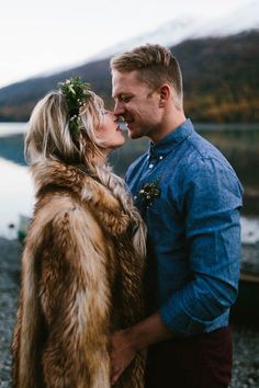 a man and woman standing next to each other in front of a body of water