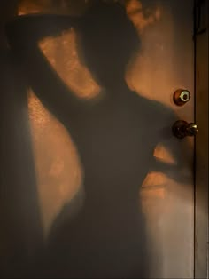 the shadow of a woman standing in front of a door with her arms behind her head