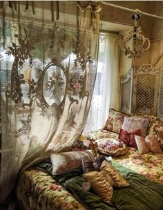 a bed sitting under a sheer curtain next to a window with curtains hanging from it