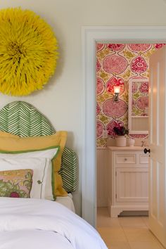 a white bed sitting next to a yellow flower on top of a headboard in a bedroom