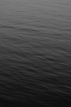 an airplane is flying over the ocean in black and white, as seen from above