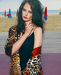 a woman in a leopard print coat posing for a photo with her arms folded over her chest