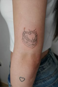 a woman's arm with a tattoo on it that has a cake in the shape of a heart