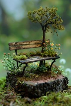 a miniature park bench with moss growing on the back and seat is sitting on top of a tree stump